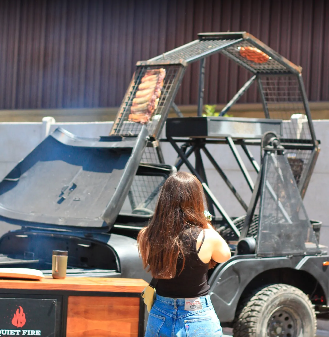 El jeep asador entero, con sus parrillas verticales desplegadas y costillas asando a la vista